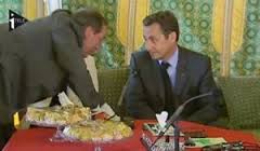 Claude Guéant penché au-dessus des mets libyens de réception, pour susurrer, sous le nez de la dame interprète, à l'oreille de Nicolas Sarkozy